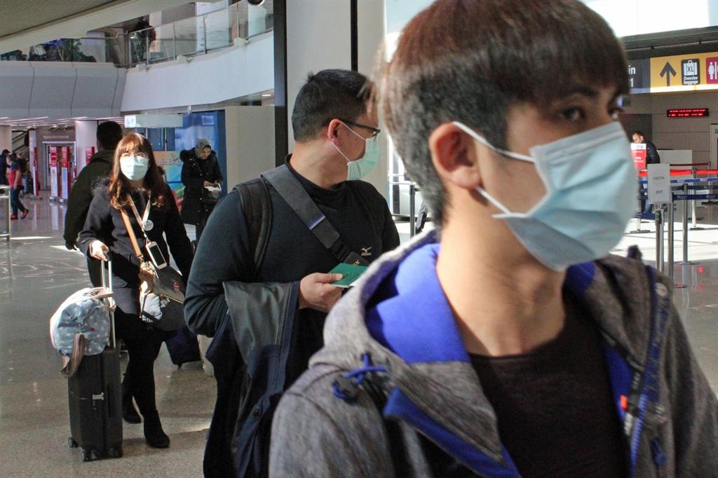 epa08255120 Asian tourists wear protective face masks at Fiumicino airport, near Rome, Italy, 28 February 2020. At least 17 people suffering from the COVID-19 disease caused by the novel SARS-CoV-2 coronavirus have died in Italy, while some 650 people have been infected, according to emergency commissioner Angelo Borrelli.  EPA/TELENEWS