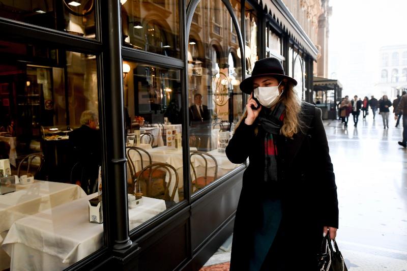 A woman wearing a sanitary mask talks on the phone as she walks in the Vittorio Emanuele Gallery shopping arcade, in downtown Milan, Italy, Monday, Feb. 24, 2020. At least 190 people in Italya€™s north have tested positive for the COVID-19 virus and four people have died, including an 84-year-old man who died overnight in Bergamo, the Lombardy regional government reported. (Claudio Furlan/Lapresse via AP)