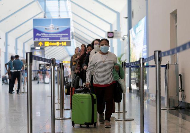People wearing masks walk next to a thermal scanner at Bandaranaike International Airport after Sri Lanka confirmed the first case of coronavirus in the country, in Katunayake
